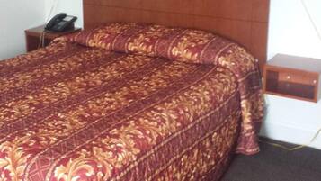 Quarto de hotel com uma cama grande, cabeceira de madeira, pintura de flores na parede e luminárias laterais.