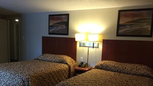A hotel room with two beds, a nightstand with a lamp, and two framed pictures on the wall. - Royal Inn Motel (Watertown)