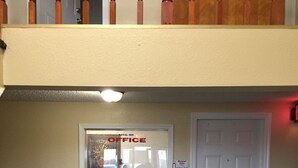 A hotel reception area with a white door, a reception desk, and a sign indicating the Royal Inn Office. - Royal Inn Motel (Watertown)