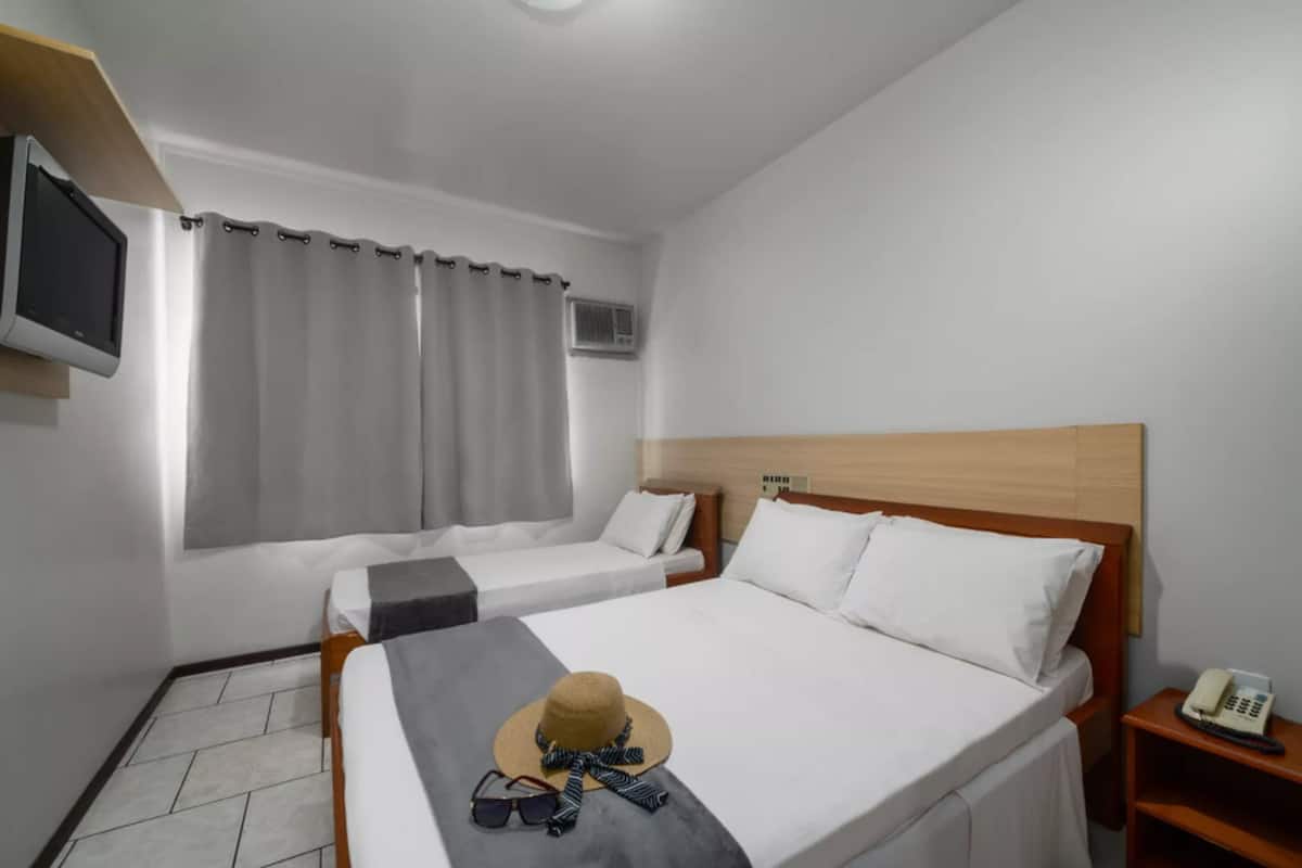 A hotel room with two beds, a TV, and a telephone on a bedside table.