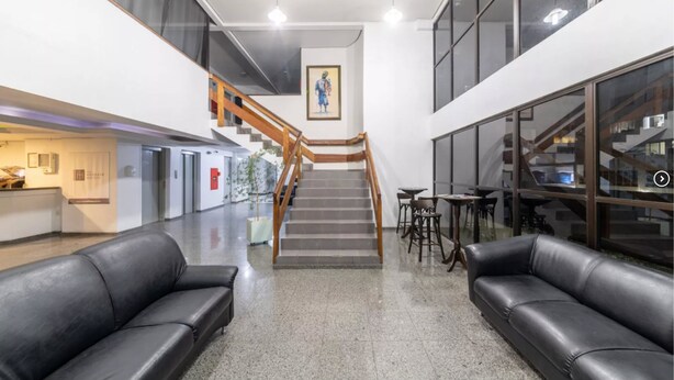 Un hall d’hôtel avec un escalier, des canapés en cuir et un comptoir d’accueil.