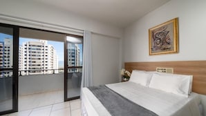 Une chambre d’hôtel avec un grand lit, une vue sur les gratte-ciel et une œuvre d’art encadrée au mur.