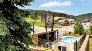 A view of the Lantern Inn with a pool area, surrounded by trees and a mountainous landscape. - Lantern Inn (Hill City)