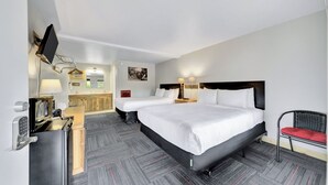 A hotel room with two beds, a desk with a computer, a TV, and a bathroom visible through an open door. - Lantern Inn (Hill City)