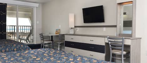Habitación de hotel con dos camas, un escritorio, una silla, un televisor y un balcón con vistas.