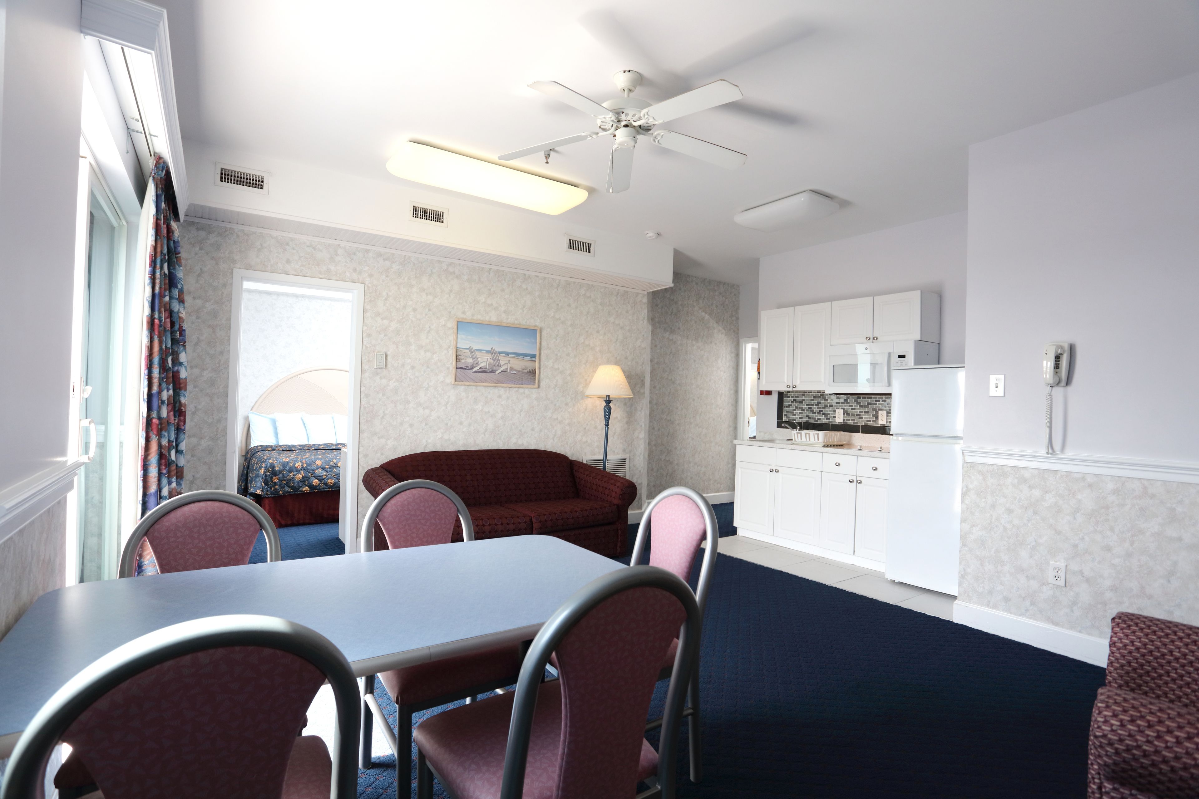 Een kleine hotelkamer met een zithoek, kitchenette en een enkel bed.