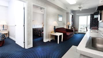 Habitación de hotel con cama, escritorio, sofá rojo, zona de comedor y vista a la ciudad.