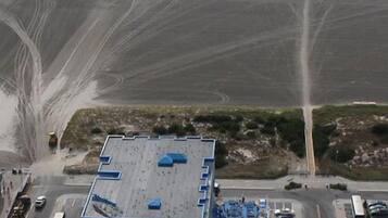 Vista aérea de un edificio con estacionamiento, junto a una playa.
