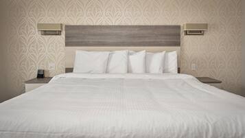 A neatly made bed with white linens and a wooden headboard. There are two bedside tables with lamps on either side of the bed.
