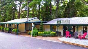A check-in general store with a green roof, surrounded by trees and outdoor seating with Adirondack chairs. - Anvil Campground (Williamsburg)