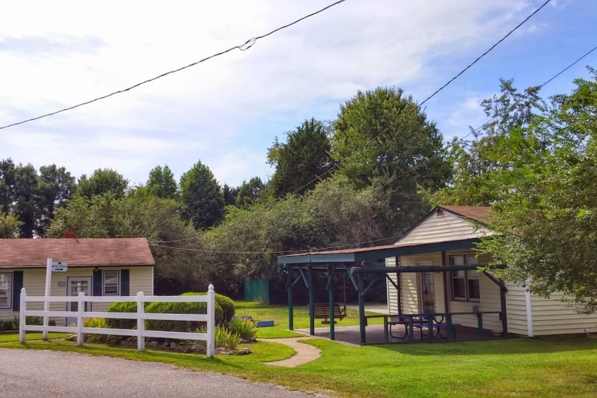 A small, single-story building with a porch and a fenced yard.