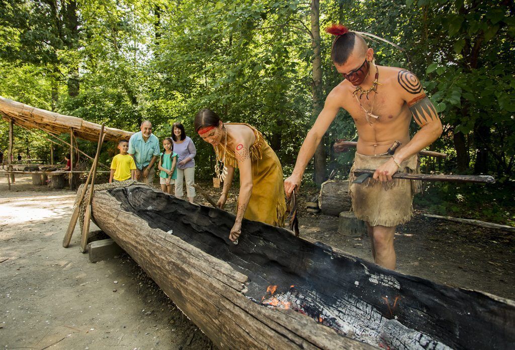 A group of people around a fire pit in a forested area.