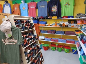 A retail store with shelves of folded clothing and a display of hats. - Anvil Campground (Williamsburg)