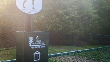 A dog waste station with a sign and a trash bin.