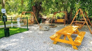 A dog waste station, swings, a picnic table, and a fenced play area. - Anvil Campground (Williamsburg)