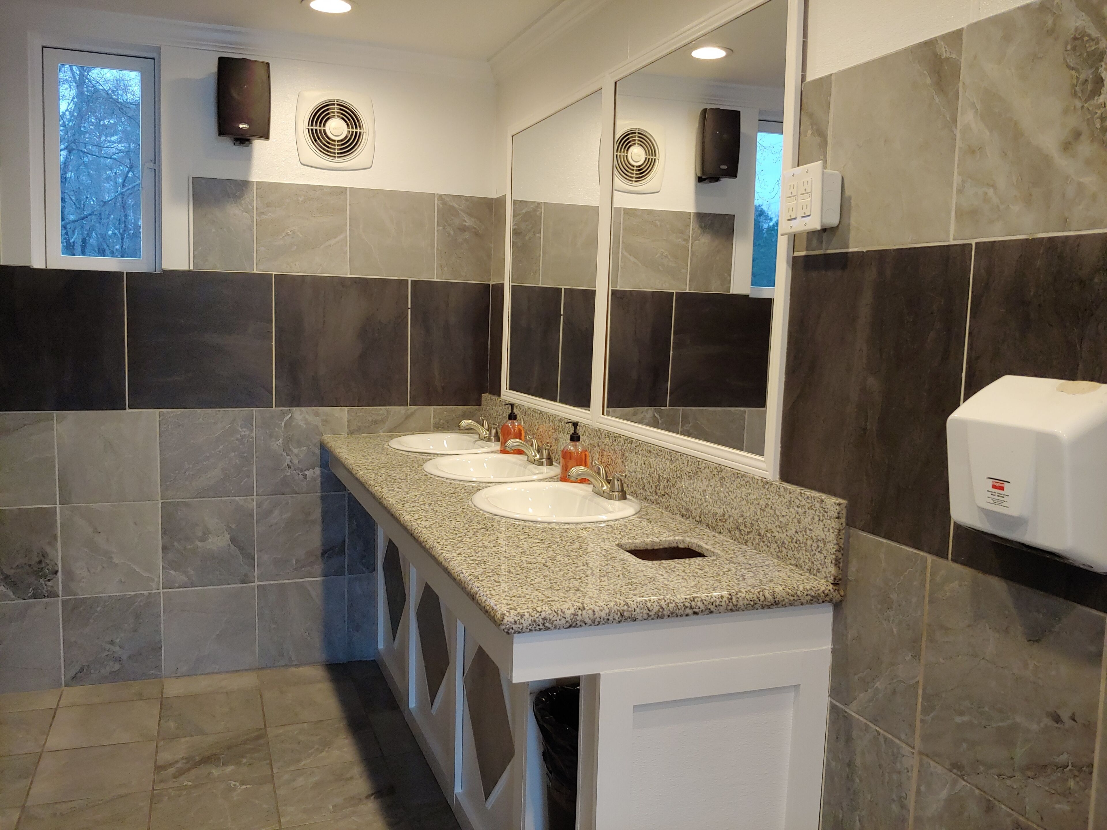 Ein modernes Badezimmer mit zwei Waschbecken, einem großen Spiegel und einem Handtrockner.