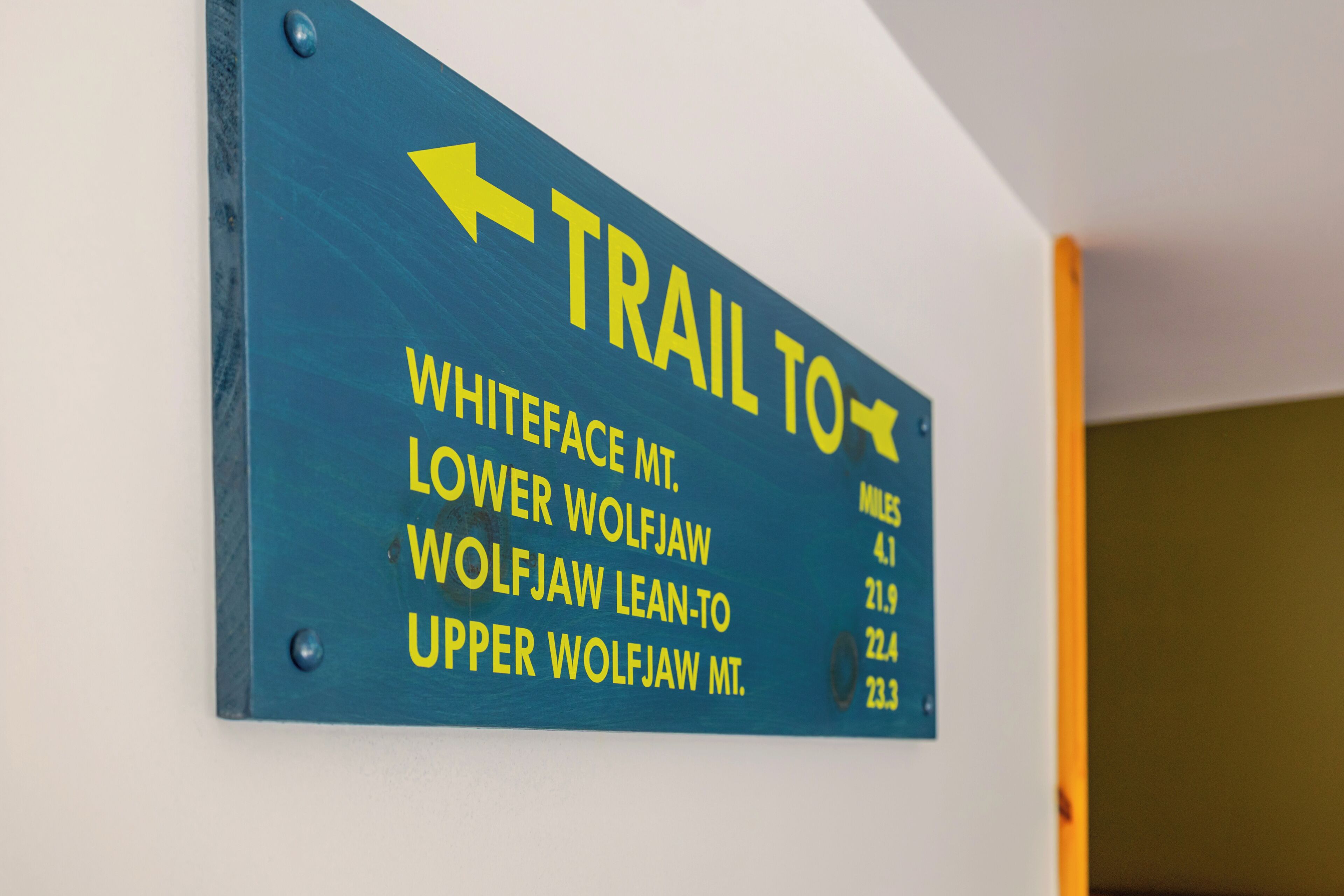 A directional sign with an arrow pointing left, listing trails to Whiteface Mt., Lower Wolfjaw, Wolfjaw Lean-to, and Upper Wolfjaw Mt.