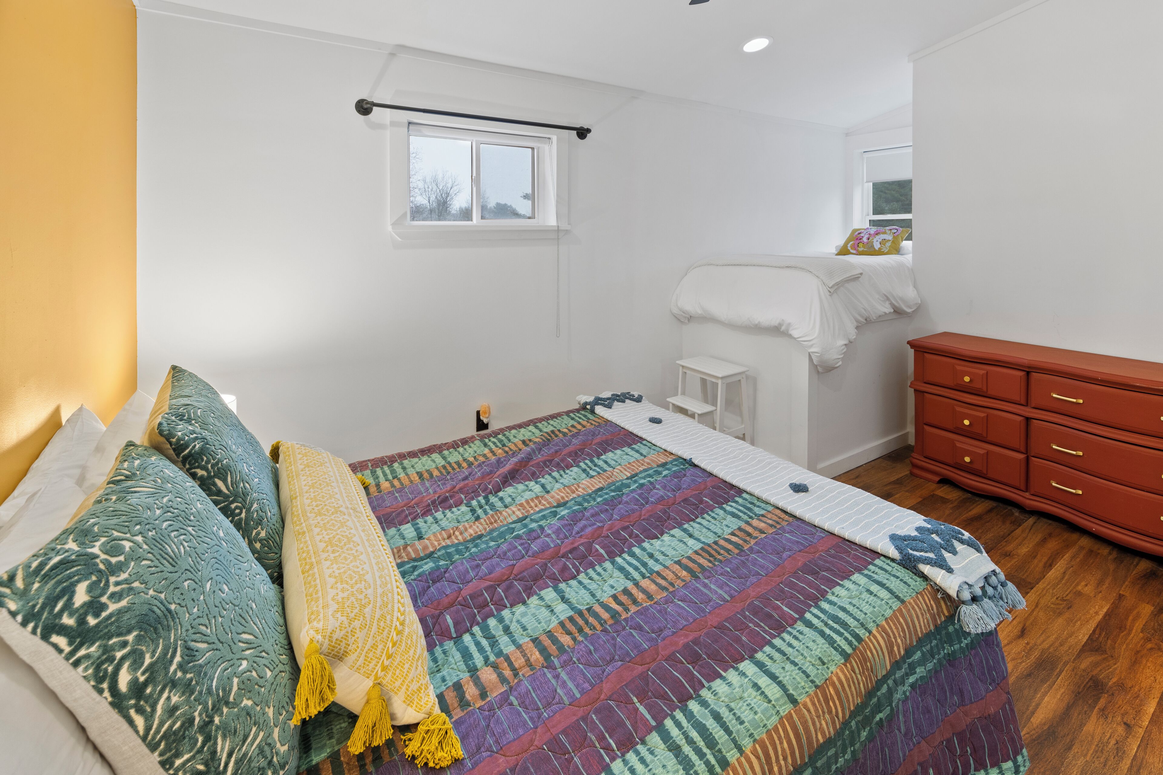 A bedroom with a bed, a window, a dresser, and a nightstand.
