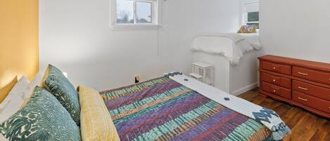 Un dormitorio con cama, ventana, cómoda y mesita de noche.