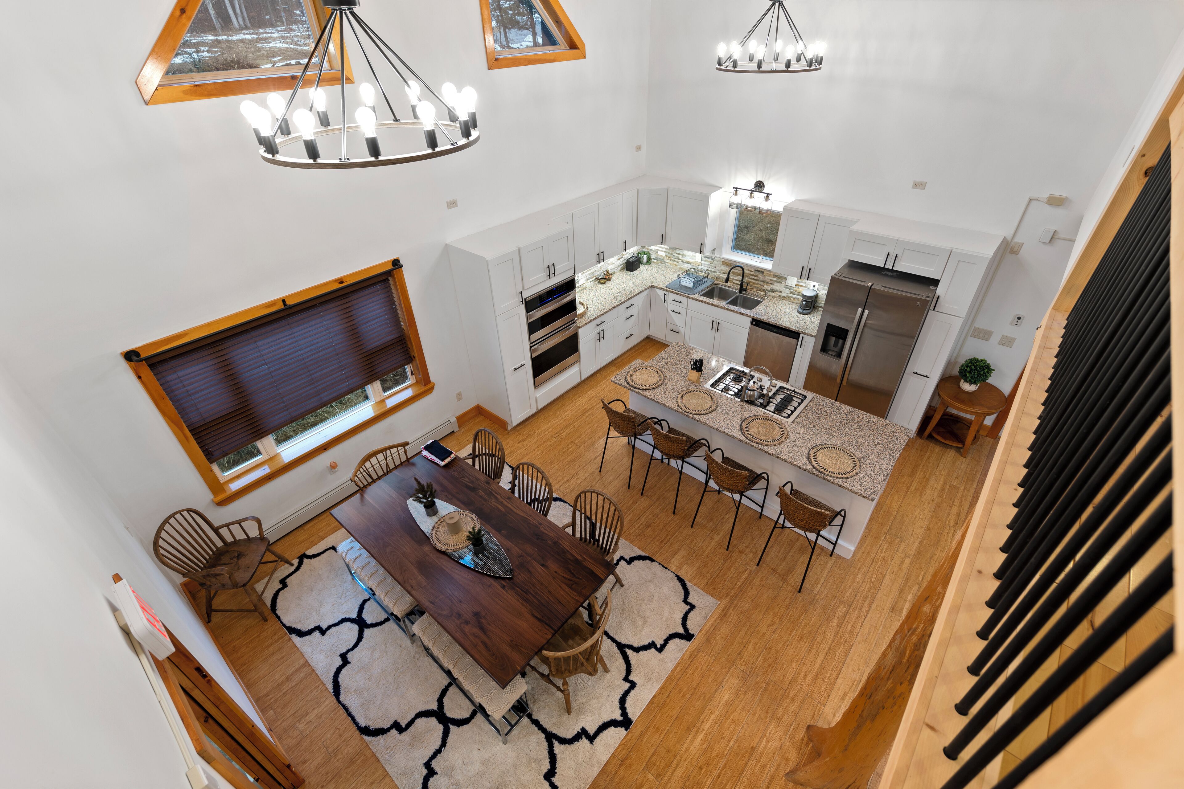 A spacious kitchen with modern appliances, a dining area with a wooden table and chairs, and a large window providing natural light.