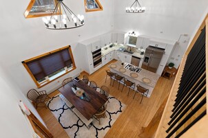 Una cocina amplia con electrodomésticos modernos, un comedor con mesa y sillas de madera, y un gran ventanal que proporciona luz natural.
