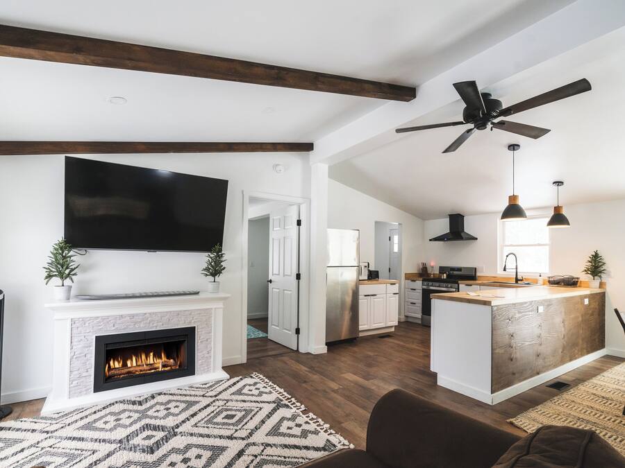 Una cocina moderna con una isla central, una chimenea y un rincón de comedor con un sofá marrón.