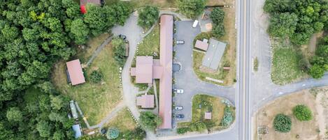 An aerial view of a residential area with a large building, multiple smaller structures, and a road.