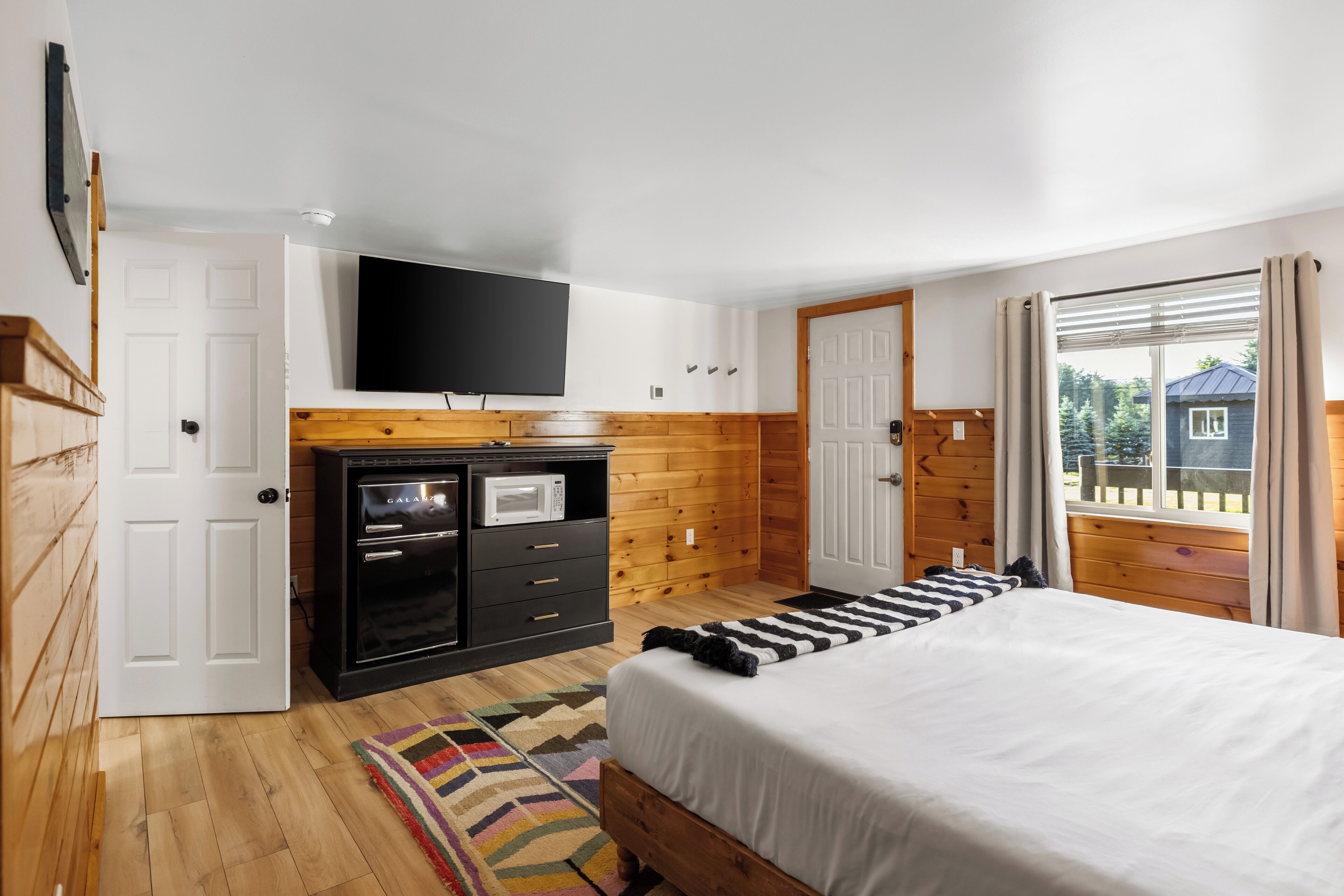 Un dormitorio con cama, televisor, microondas y armario de madera.