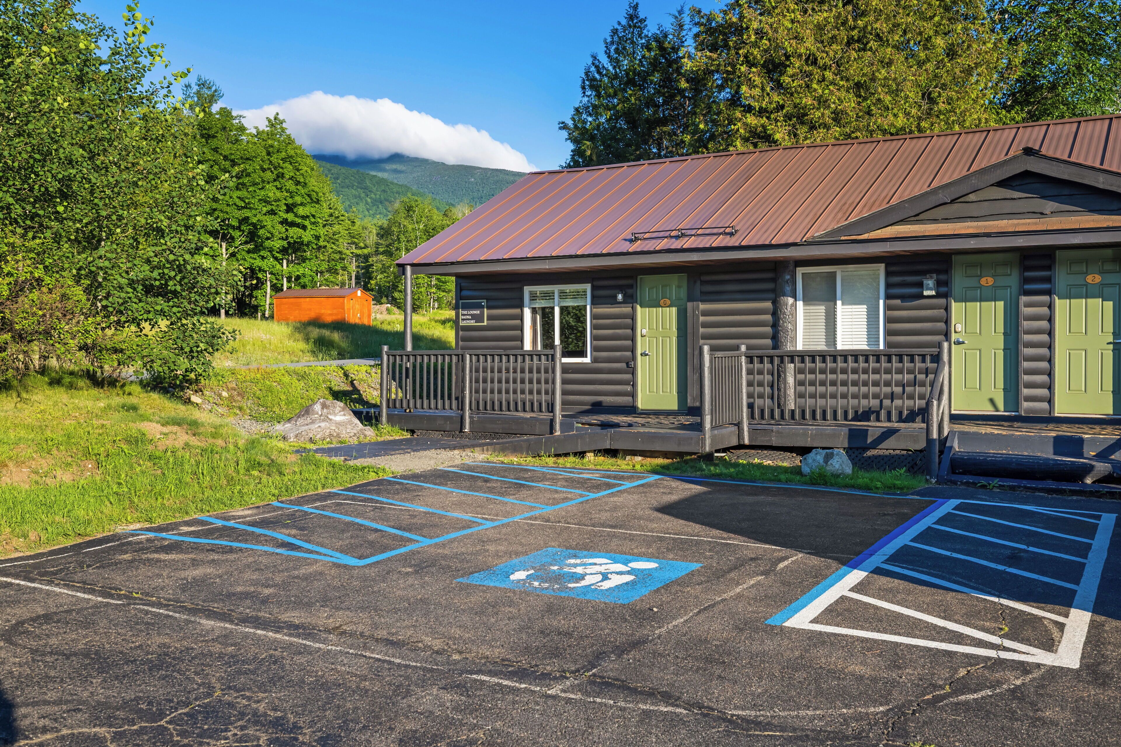 A cabin with a metal roof, a porch, and a parking area with handicapped spaces.