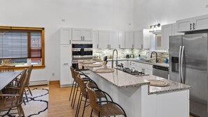 Eine moderne Küche mit weißen Schränken, einem Edelstahlkühlschrank und einer zentralen Kochinsel mit Barhocker.