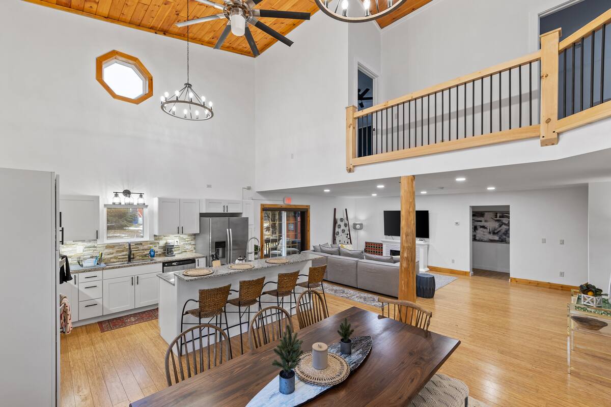 A spacious kitchen with a central island, wooden ceiling, and a dining area with a wooden table and chairs.