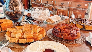 A table with various desserts and a vase of flowers. - Hotel Pontal de Tiradentes (Tiradentes)