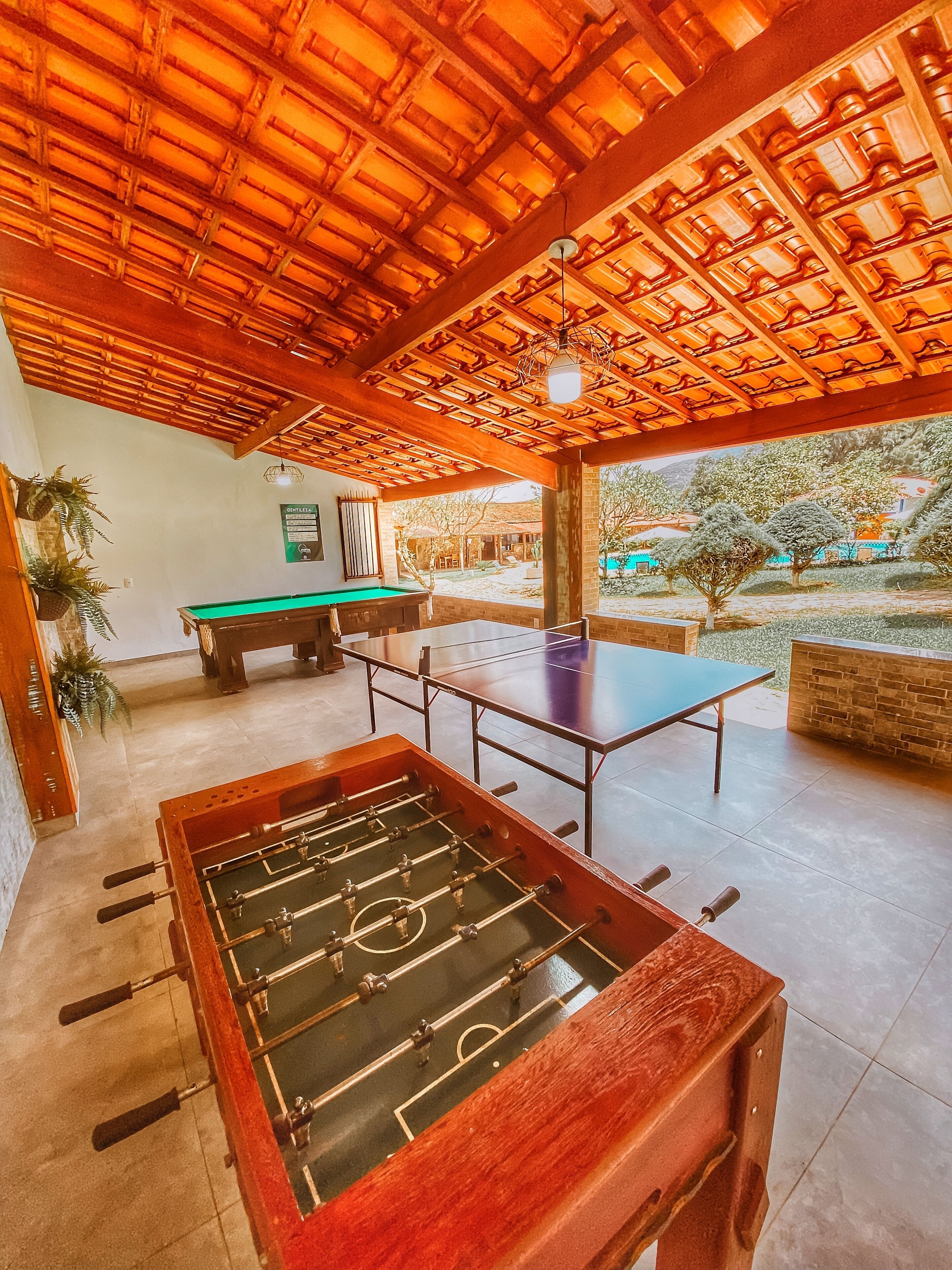 An indoor recreational area with a foosball table, ping pong table, and pool table.