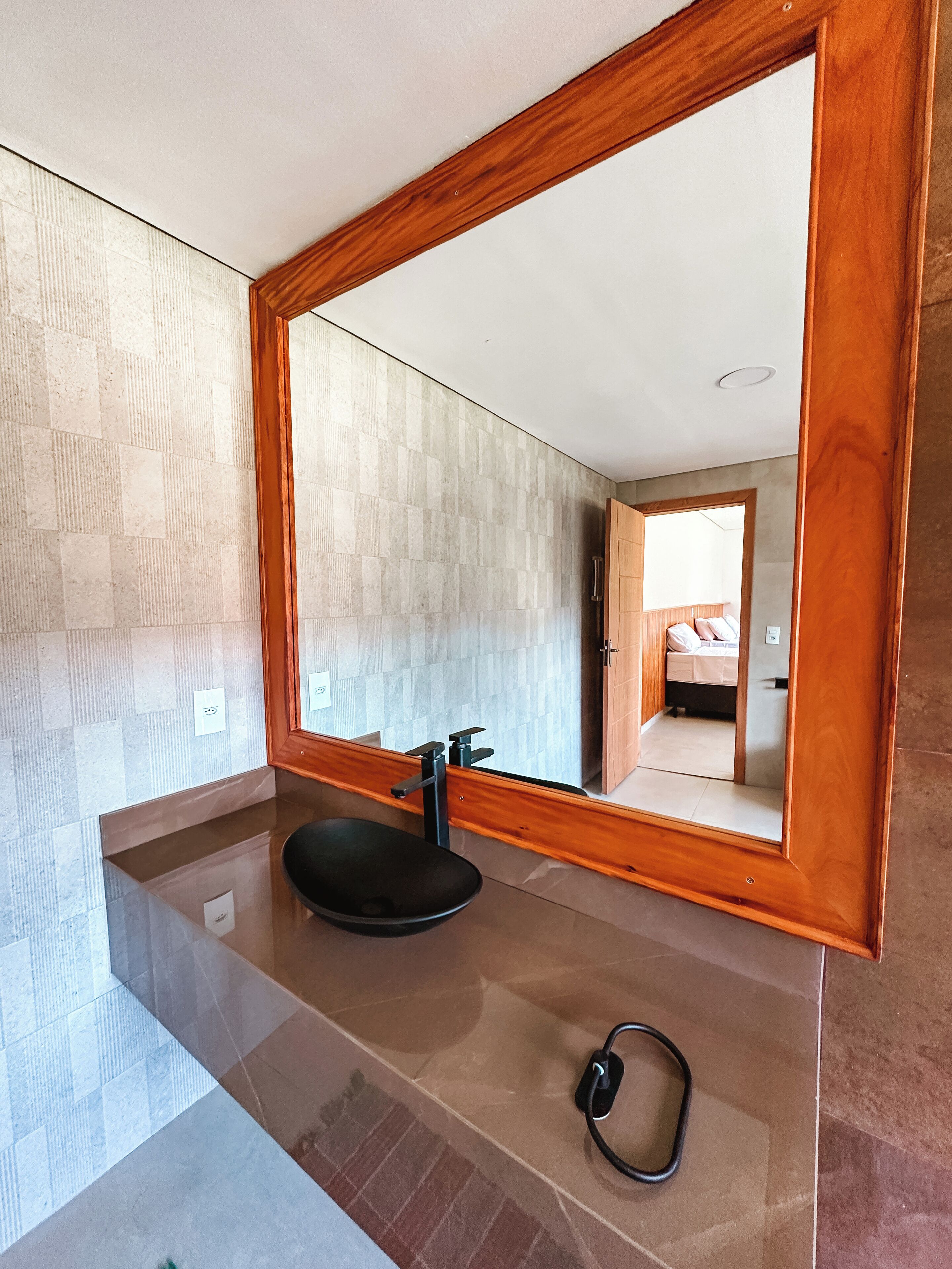 Uma casa de banho moderna com um espelho grande, uma sanita preta e um suporte de toalha.