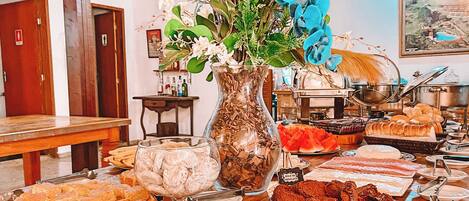 A buffet with various desserts and a decorative vase with flowers.