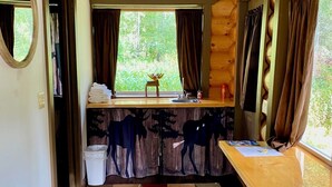 Une cabane chaleureuse avec un sol à carreaux, une table en bois et une fenêtre avec des rideaux.