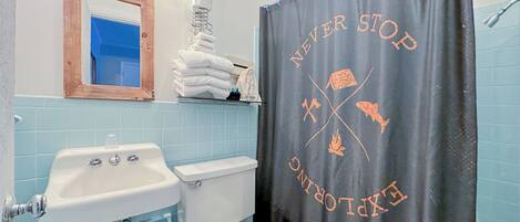 Un baño con lavamanos, inodoro y cortina de ducha con motivos náuticos.