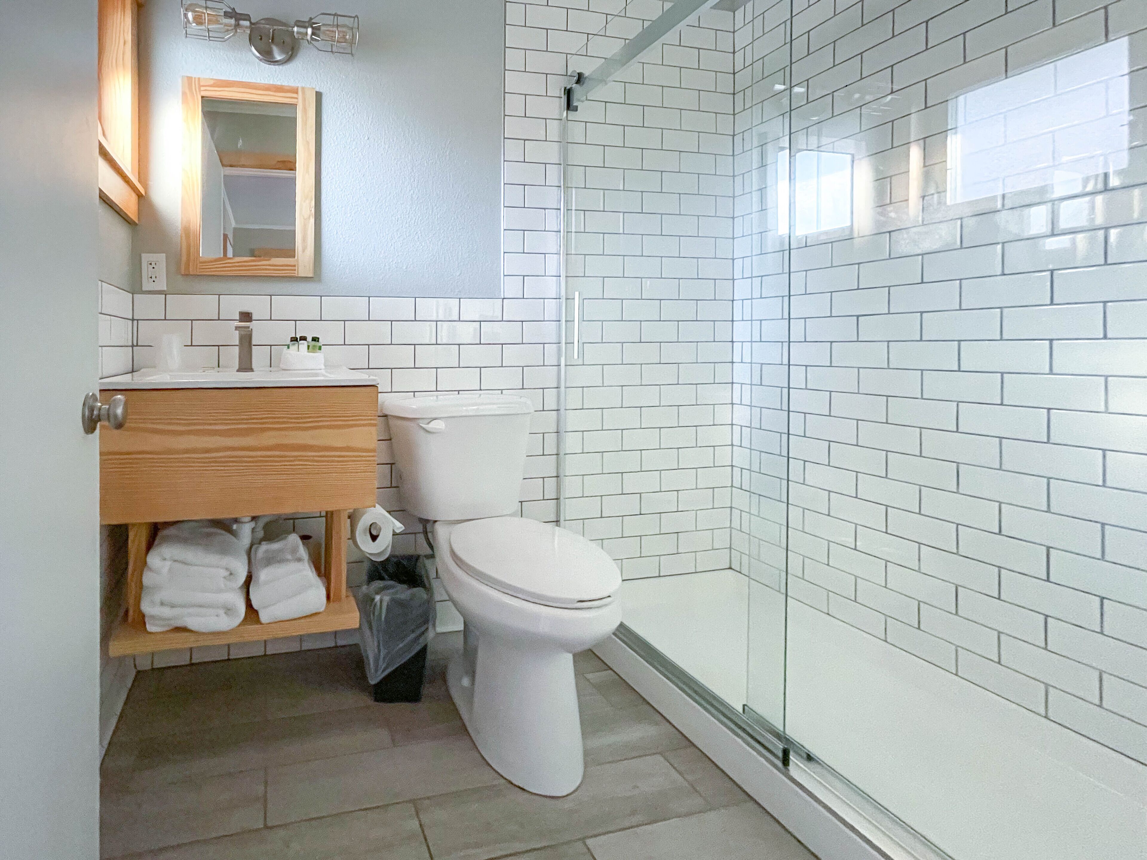 Une salle de bain comprenant des toilettes, un lavabo avec un miroir et un espace douche doté de portes en verre.
