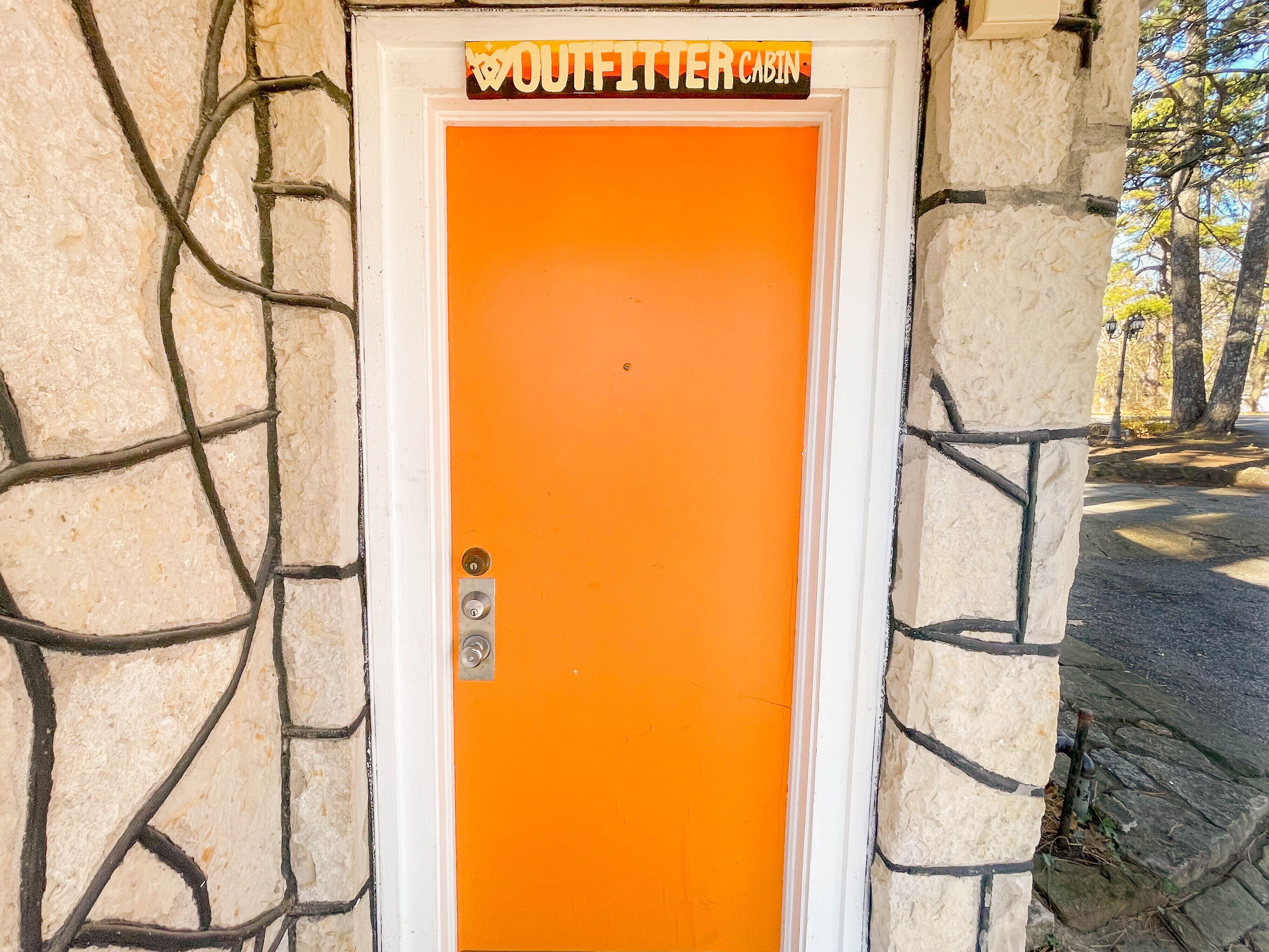 An orange door with a sign above it that reads "OUTFITTER CABIN."