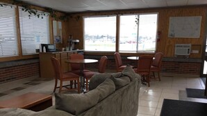 Un restaurante con pared de ladrillo, techo de madera y ventanas grandes. Hay un sofá, una mesa y sillas.
