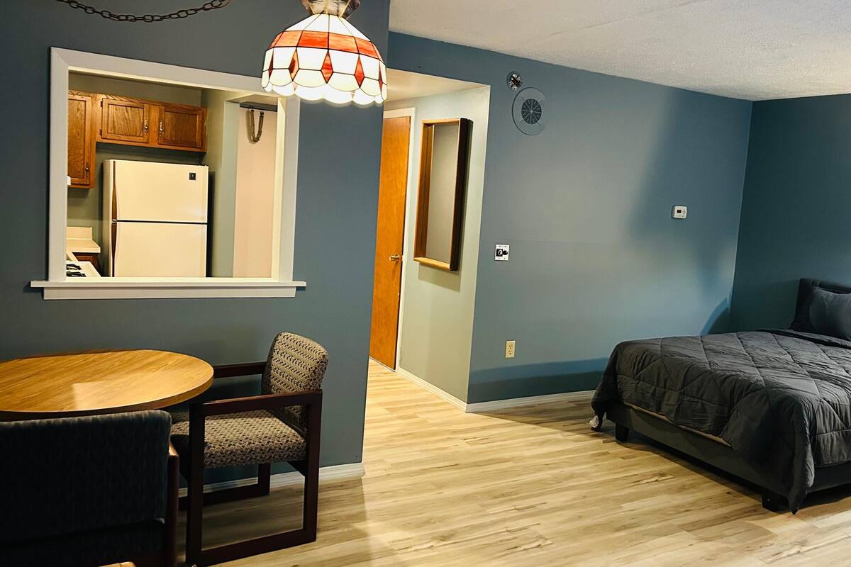 A compact bedroom with a bed, a small table, and a chair.