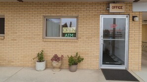 A building with a brick facade, an open sign, an ATM, and a door labeled "OFFICE". - Capital O Swan Inn Comstock Park (Comstock Park)