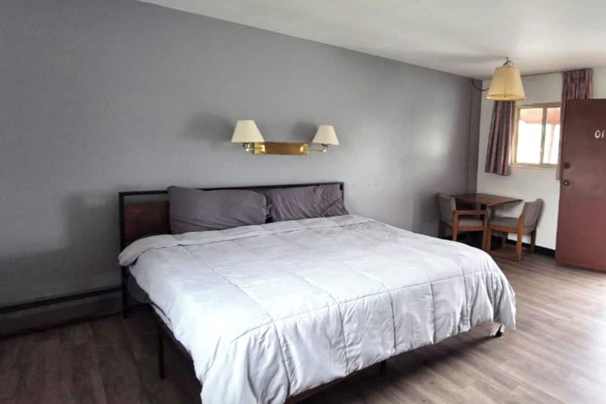 A bedroom with a bed, a desk, and a chair.