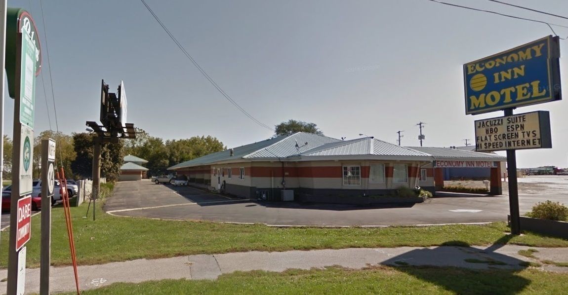 A motel with a sign advertising amenities like a Jacuzzi suite, HBO, ESPN, flat-screen TVs, and high-speed internet.