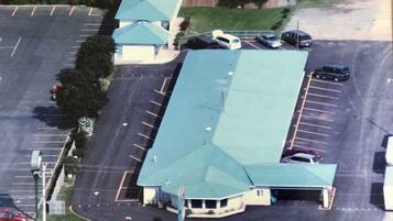 An aerial view of a parking lot with a building featuring a green roof and a single-story structure.
