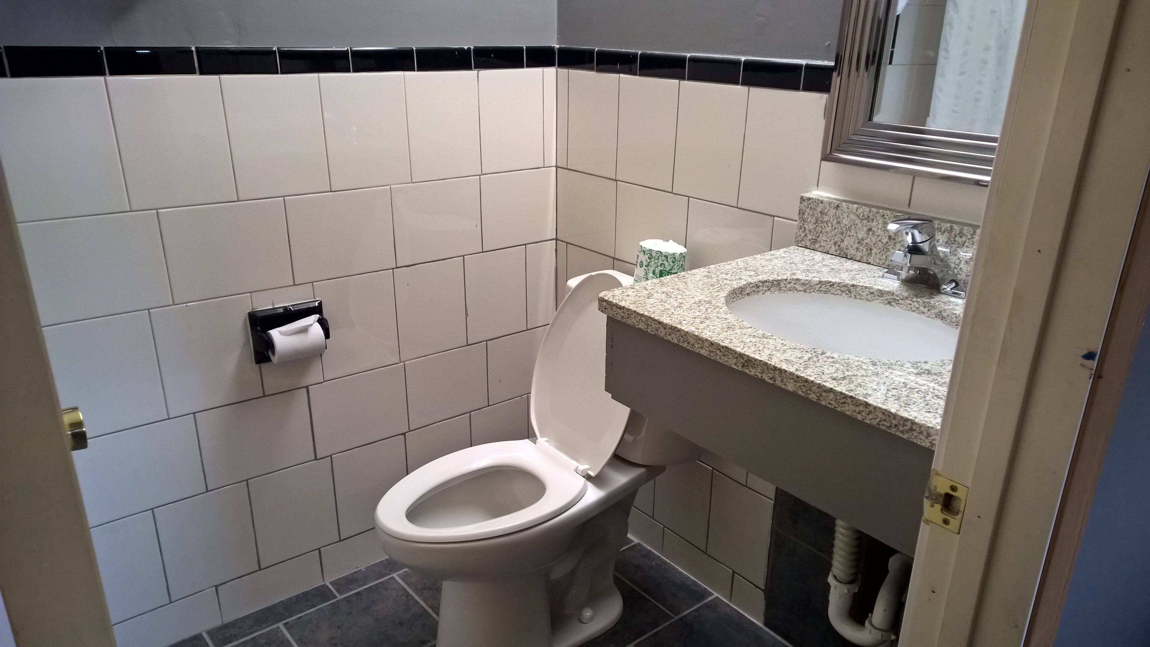 Un baño con inodoro, lavamanos y dispensador de toallas de papel.