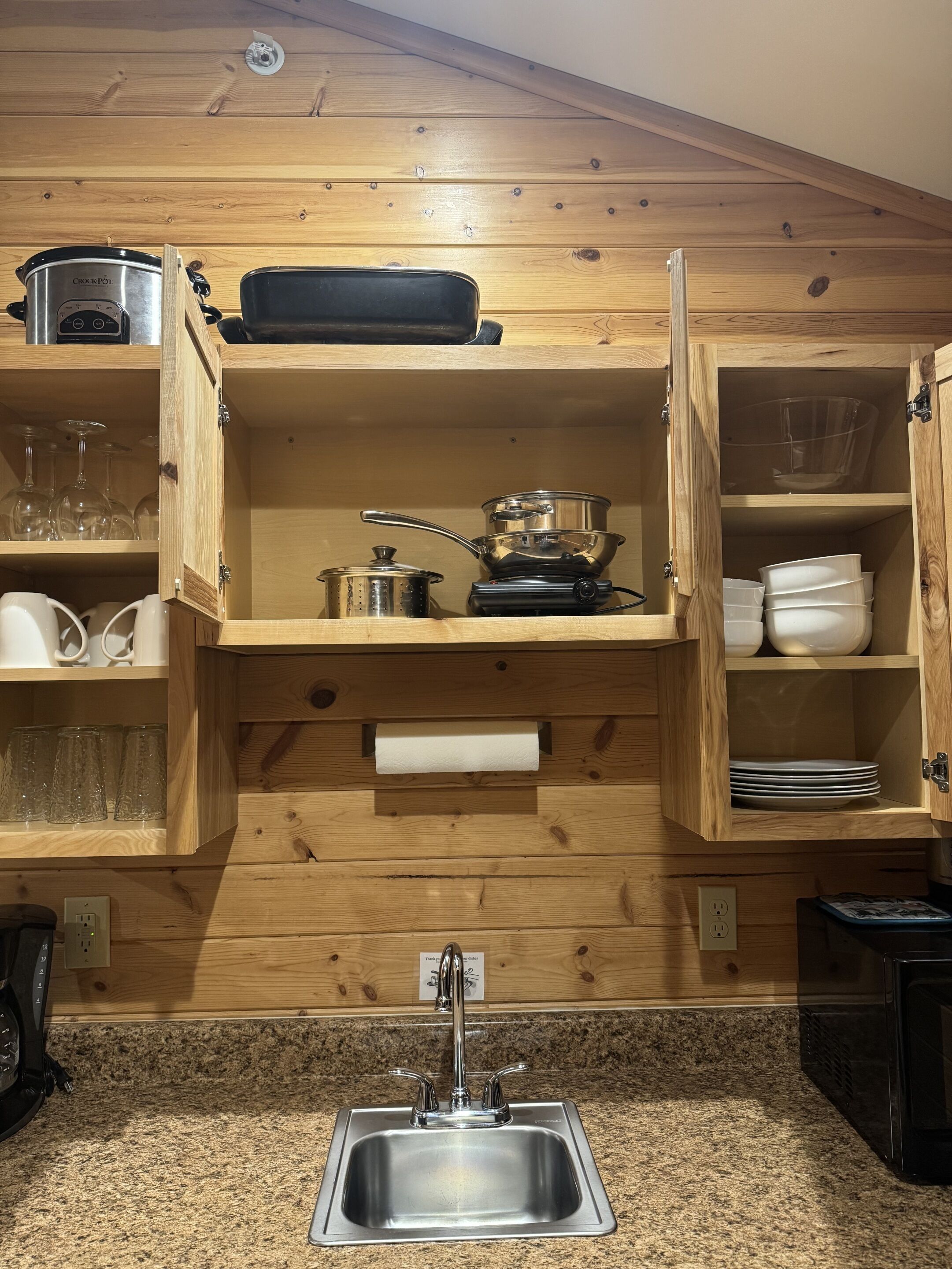 Una cocina con armarios de madera, un lavamanos de acero inoxidable y varios electrodomésticos.