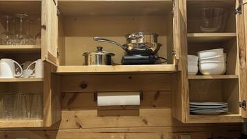 Una cocina con armarios de madera, un lavamanos de acero inoxidable y varios electrodomésticos.
