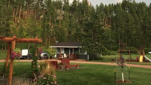A house with a deck, surrounded by a forest. - Black Elk Resort Cottages and RV Park (Hill City)