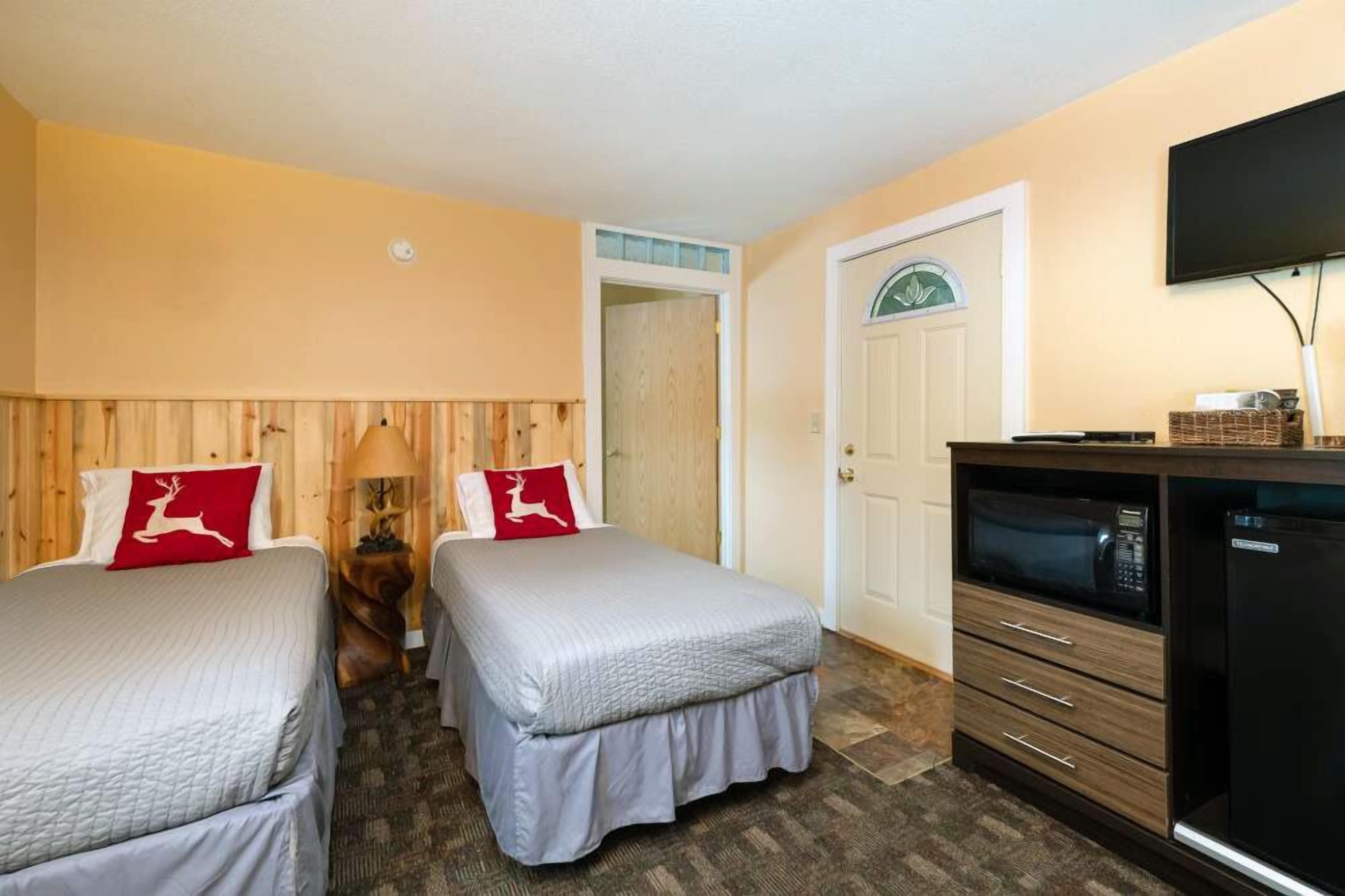 A hotel room with two beds, a television, and a minibar.